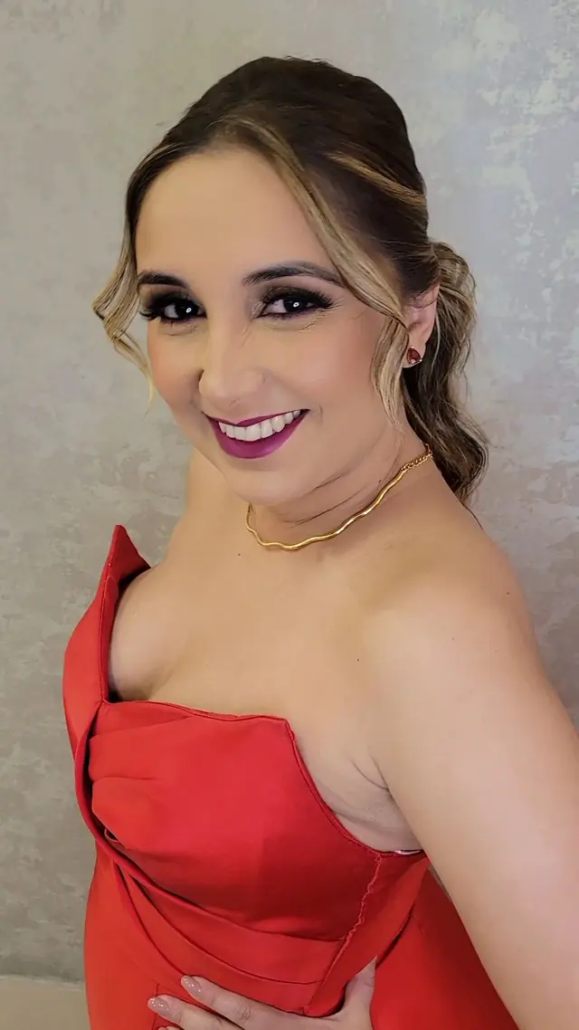 Cliente de vestido vermelho com maquiagem de festa e cabelo preso